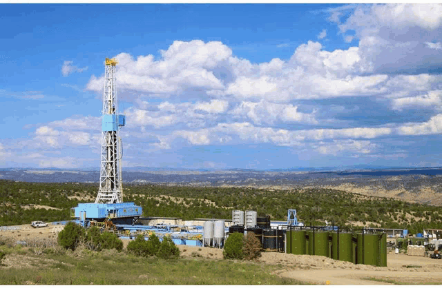 a large oil rig in the middle of a desert with mountains in the background