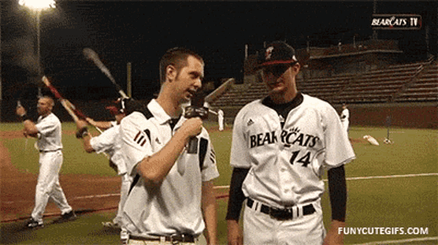 a baseball player with the number 14 on his jersey talks to a reporter