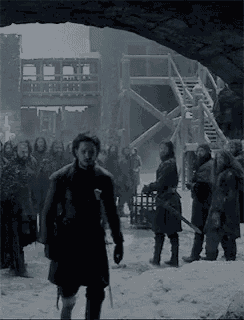 a group of men are standing in the snow holding swords and a sword .