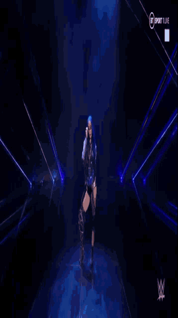 a woman with blue hair is laying down on a stage in a dark room .