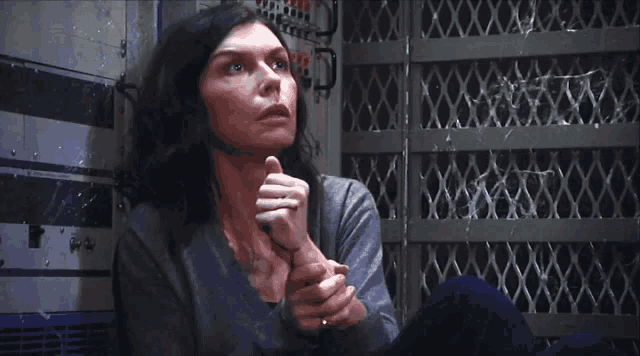 a woman is sitting in front of a fence and looking at something