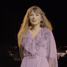 a woman in a purple dress is standing in front of a crowd .