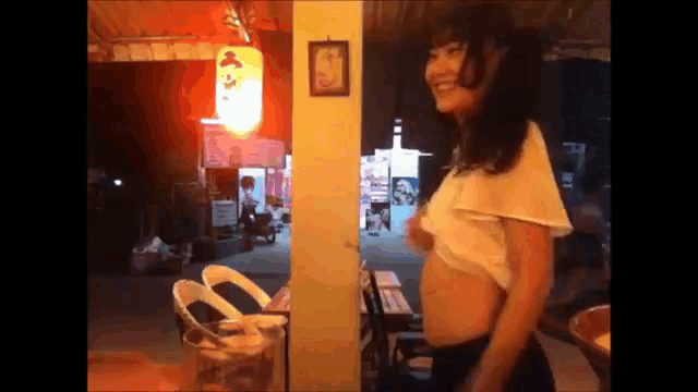 a woman in a white top is standing in front of a wall with a picture on it that says ' a ' on it