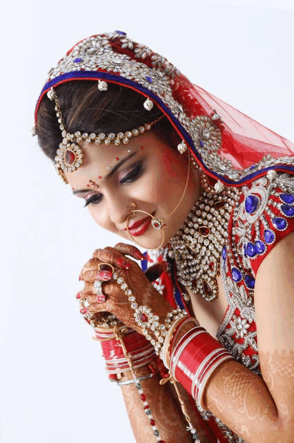 a woman in a red and silver dress with a nose ring is praying