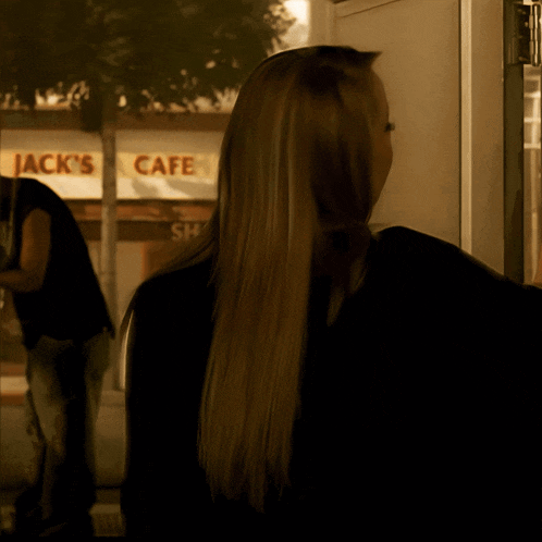 a woman is standing in front of a jack 's cafe