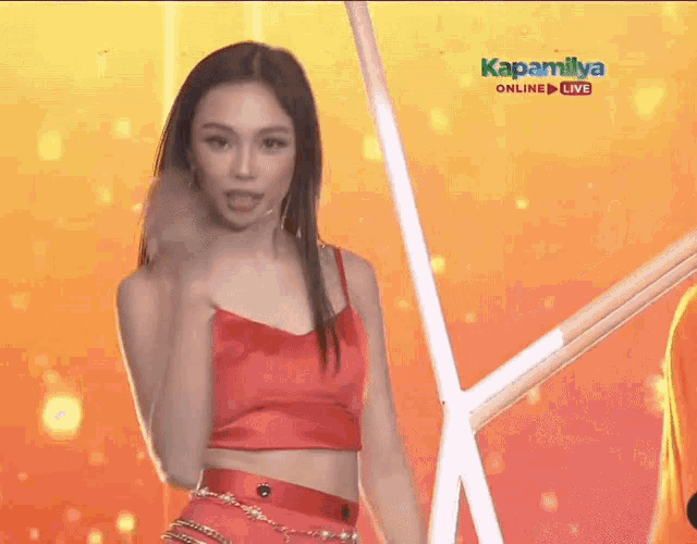 a woman in a red crop top is dancing in front of a screen that says kapamilya