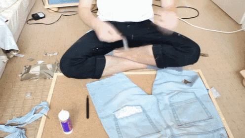a person is sitting on the floor with their legs crossed and a bottle of acrylic paint in front of them
