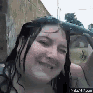 a woman is smiling while taking a selfie with a water gun in her hand .