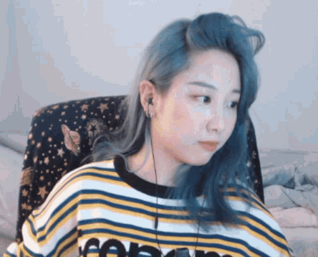 a woman with blue hair is wearing a yellow and white striped shirt that says supreme