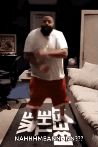a man in a white shirt and red shorts is dancing on a table .