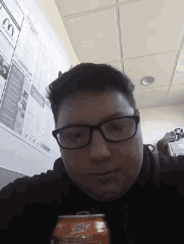 a man wearing glasses is holding a mountain dew can