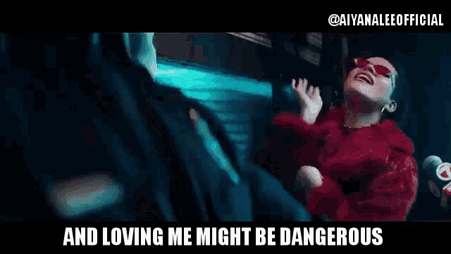 a woman in a red fur coat is sitting next to a man in a black suit and loving me might be dangerous .