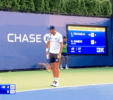 a man holding a tennis racquet on a tennis court with a chase sign behind him