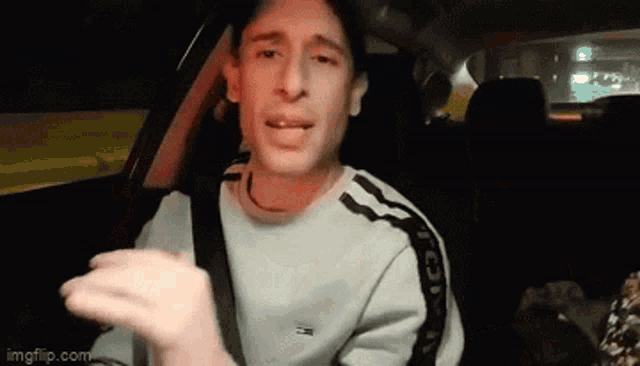 a man is sitting in the back seat of a car wearing a tommy hilfiger shirt