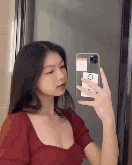 a young woman is taking a selfie in the mirror with her phone .