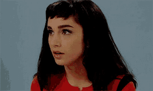 a close up of a woman 's face wearing a red shirt