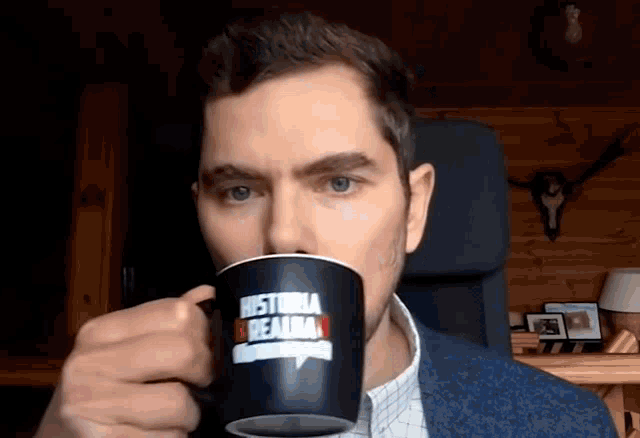 a man is drinking from a black mug that says historia realba on it