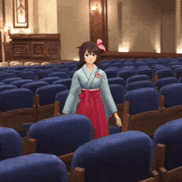 a girl in a kimono is standing in an auditorium filled with blue seats
