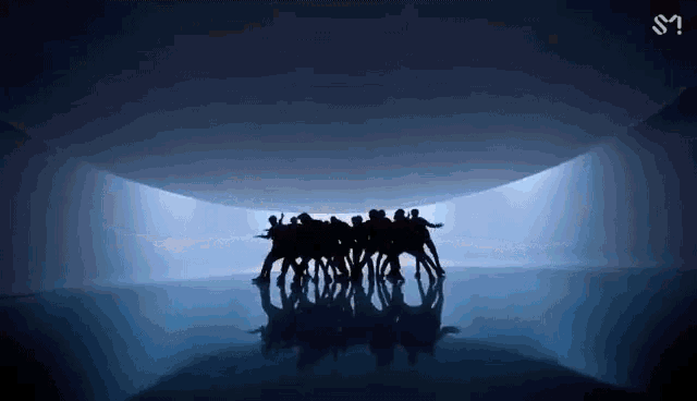 a group of people are dancing in a dark room with their reflection in the water .