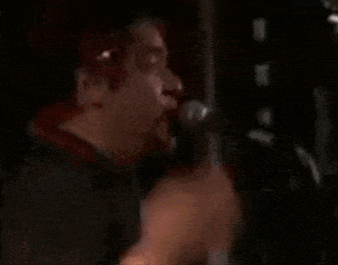 a man with red hair is singing into a microphone with his mouth open .