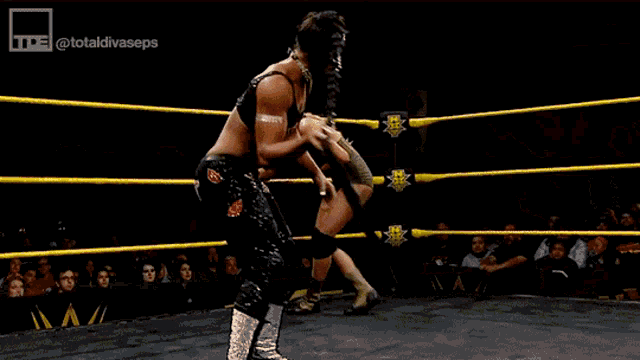 a man is wrestling another man in a wrestling ring with a crowd watching .