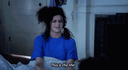 a woman is laying in bed with a messy hairdo and says `` this is the life '' .