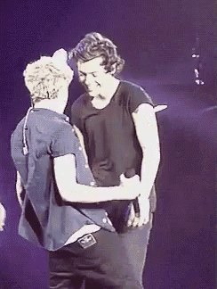 two men are hugging each other on a stage and one of them is wearing a black shirt .