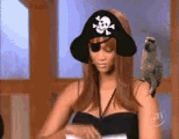 a woman wearing a pirate hat and eye patch with a parrot on her shoulder .