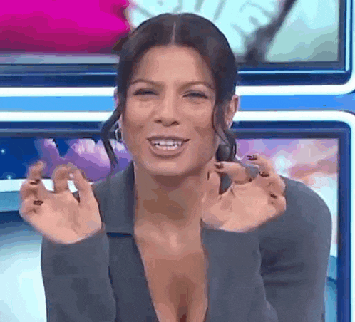 a woman with a very plunging neckline is making a funny face with her hands .