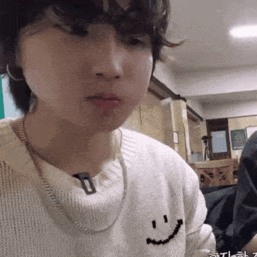 a person wearing a white sweater with a smiley face on the front