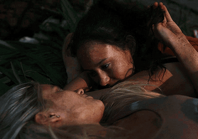 two women are laying on the ground and one of them is holding the other 's hand