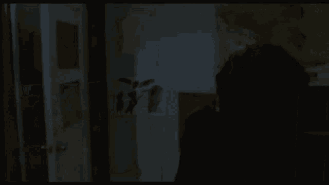 a woman is standing in a dark room with a painting on the wall behind her