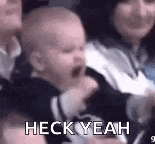 a baby is crying in a crowd of people while a woman holds it .