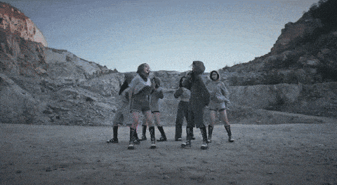 a group of people are standing in a circle on a dirt field