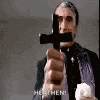 a man in a suit is holding a cross in his hand and pointing it at the camera .