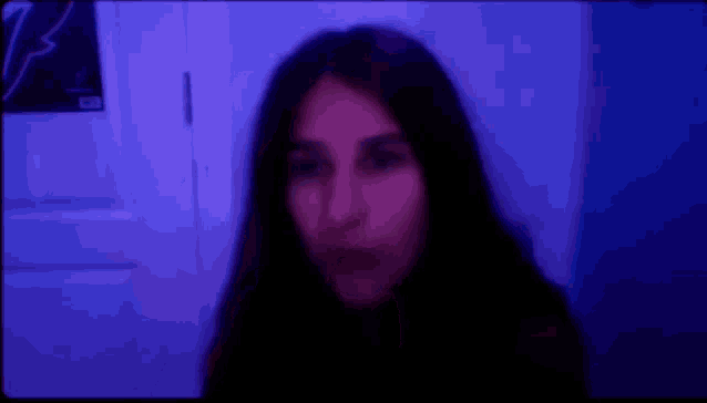 a blurry picture of a woman 's face in a dark room with a purple light behind her .