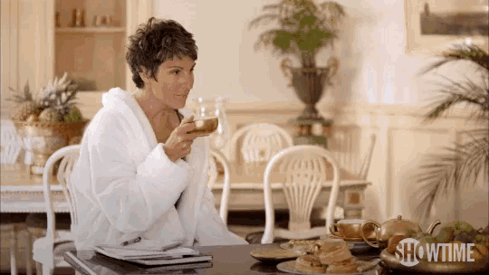 a woman sitting at a table drinking a cup of tea with showtime written in the corner