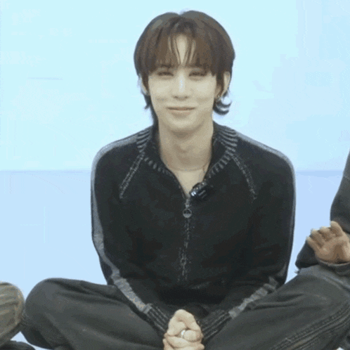 a young man sitting on the floor with his legs crossed