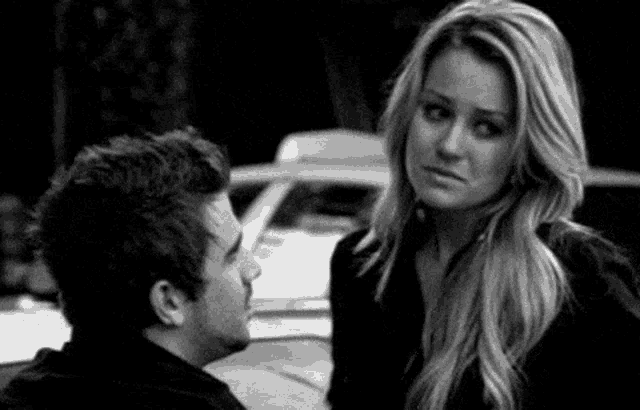 a man and a woman are standing next to each other and looking at each other in a black and white photo .