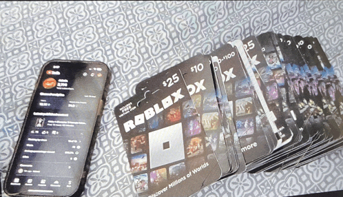 a stack of roblox cards next to a smart phone