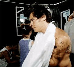 a shirtless man with a towel around his neck has a tattoo on his arm that says ' ' ' '