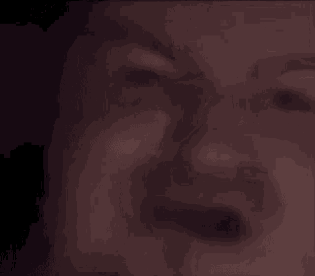 a close up of a man 's face in a dark room with his eyes closed .