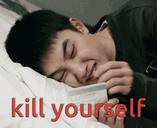 a man laying on a bed holding a credit card with the words kill yourself written on the bottom