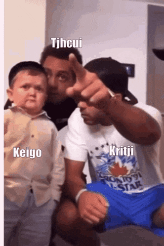 a man is pointing at a little boy while another man holds a little boy .
