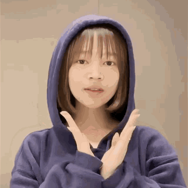 a woman wearing a blue hoodie is making a funny face .