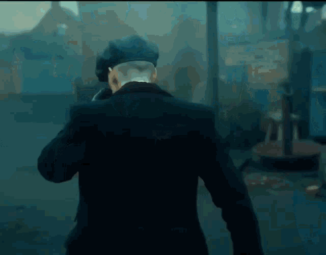 a man in a suit and hat is walking down a street in the fog .