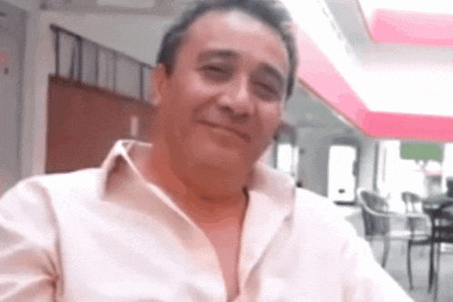 a man in a white shirt is smiling with his shirt open