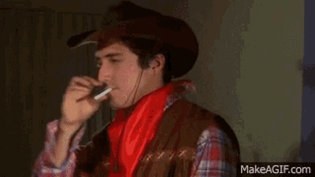a man dressed as a cowboy is brushing his teeth with cotton candy .