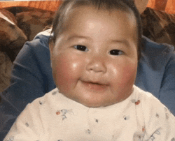 a baby with a blue shirt on is smiling