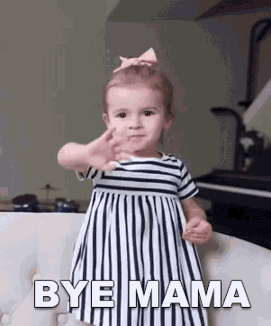 a little girl in a striped dress is sitting on a couch and waving .